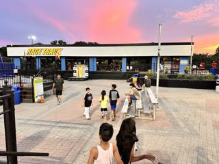 Outdoor plaza at Alley Cats Hurst before the Race Track sign at sunset.
