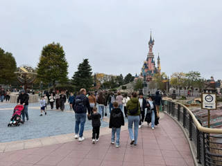 Guests cross Central Plaza with Sleeping Beauty Castle rising in the background.