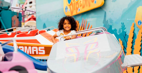 Uma criança sorri num carro branco e laranja da Wave Jumper.