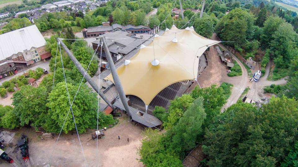 Luftaufnahme des Elspe Festivals mit dem großen Dach der Naturbühne im Mittelpunkt des bewaldeten Geländes.