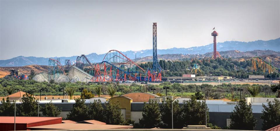 Exterior panorama bringing together the Twisted Colossus structure, colourful coaster tracks, tall towers and the Valencia hills.
