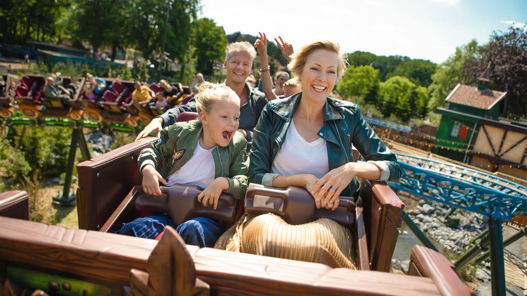 Eine Mutter und ihr Kind lachen in einem Wagen von Max + Moritz, während sich hinter ihnen die Farben der beiden Lausbuben kreuzen.