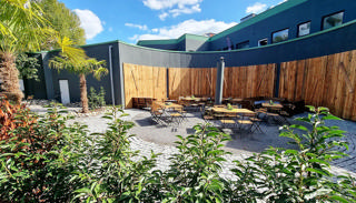 Begrünter Biergartenhof des Alma Parks bei Tageslicht.