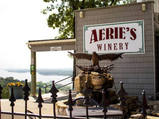 Entrada histórica do Aerie’s Resort & Winery com a águia esculpida e o letreiro acima do rio.