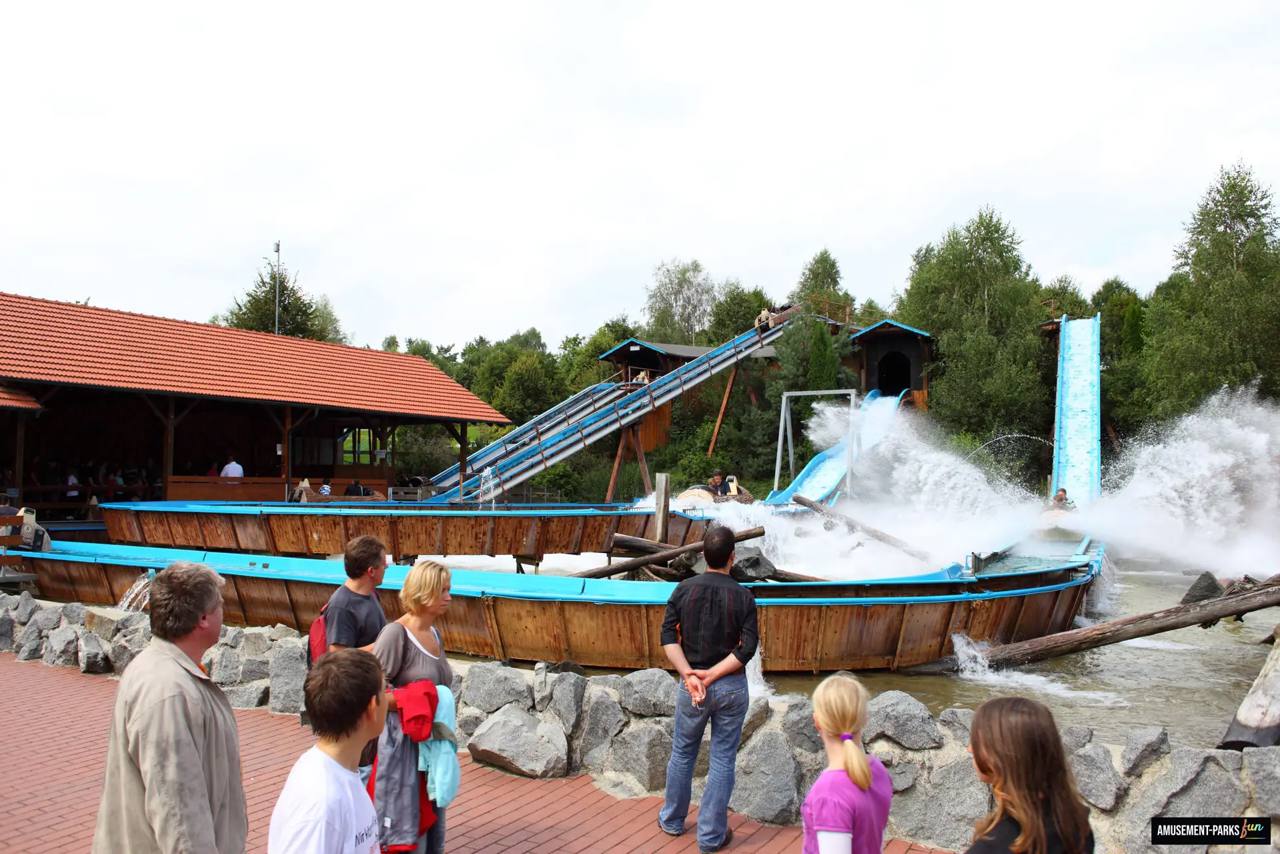 Een boot van Wildwasserbahn daalt in Bayern-Park tussen rotsen en begroeiing over de waterbaan.