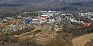 Vista aérea do Six Flags America, das montanhas-russas e do parque aquático entre o bosque.