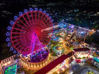 Panorama aéreo noturno do Anjo World com a roda-gigante e as diversões iluminadas.