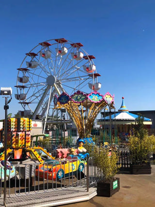 Family rides beneath the white Ferris wheel at Loos Parc