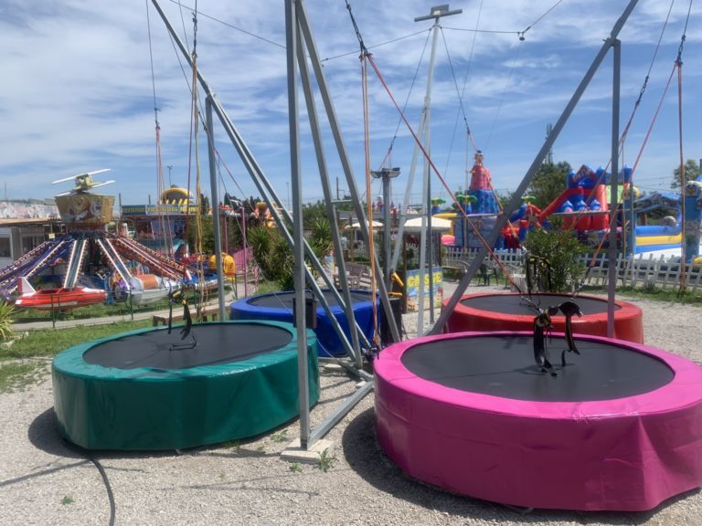 Panorama of Fiesta Parc with several family rides beneath the Mediterranean sky.