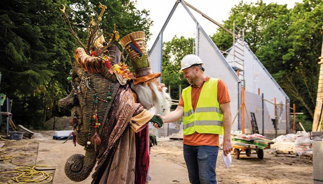 The Story Collector greets the site manager in front of the Fairy Tale Library structure.