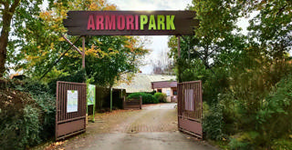 Portão aberto do Armoripark entre sebes e árvores de outono.