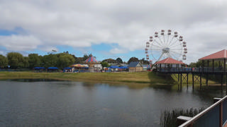 A roda-gigante, o carrossel e as atrações familiares do Adventure Park Geelong vistos a partir do lago.
