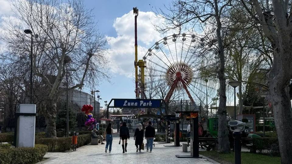 Entrée du lunapark en 2026: ingang, reuzenrad en toren zijn zichtbaar vanaf het pad.
