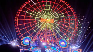 A Sun Wheel iluminada sobre o lago de Da Nang Downtown ao anoitecer.